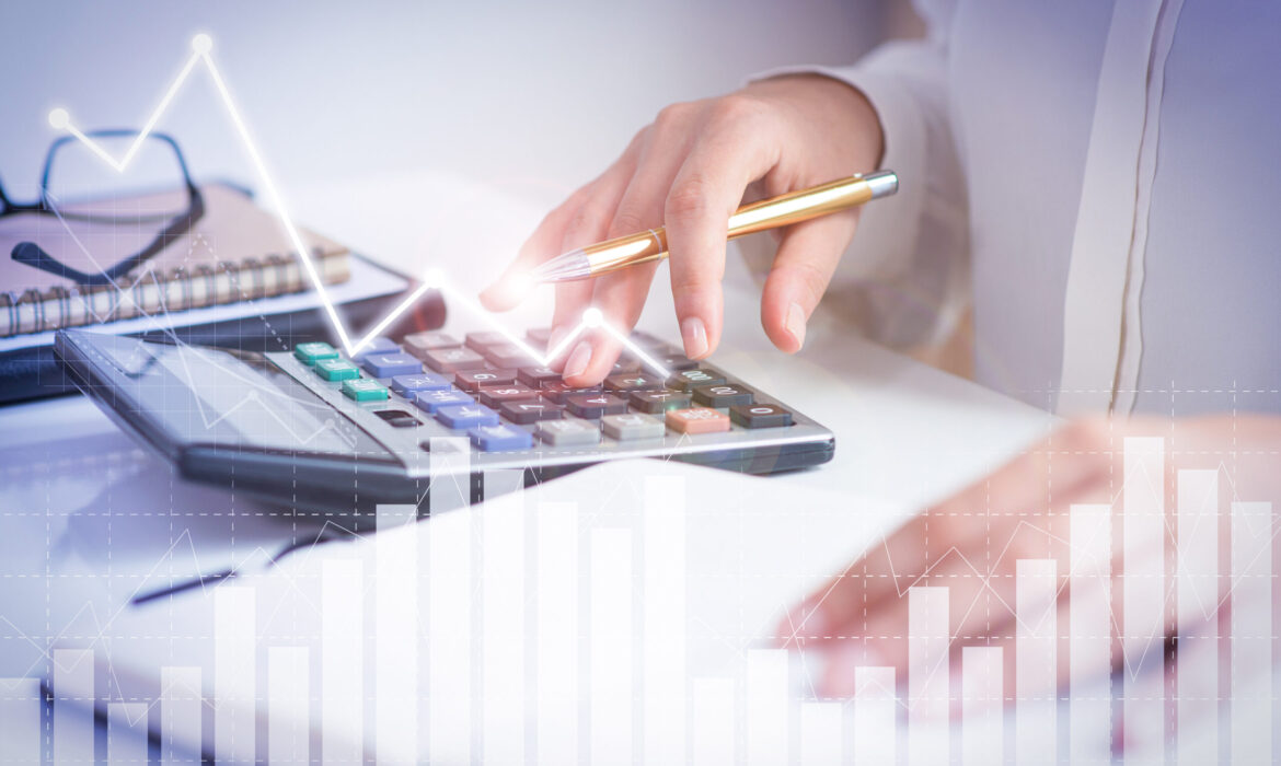 Accountant calculating profit with financial analysis graphs. Notebook, glasses and calculator lying on desk. Accountancy concept. Cropped view.