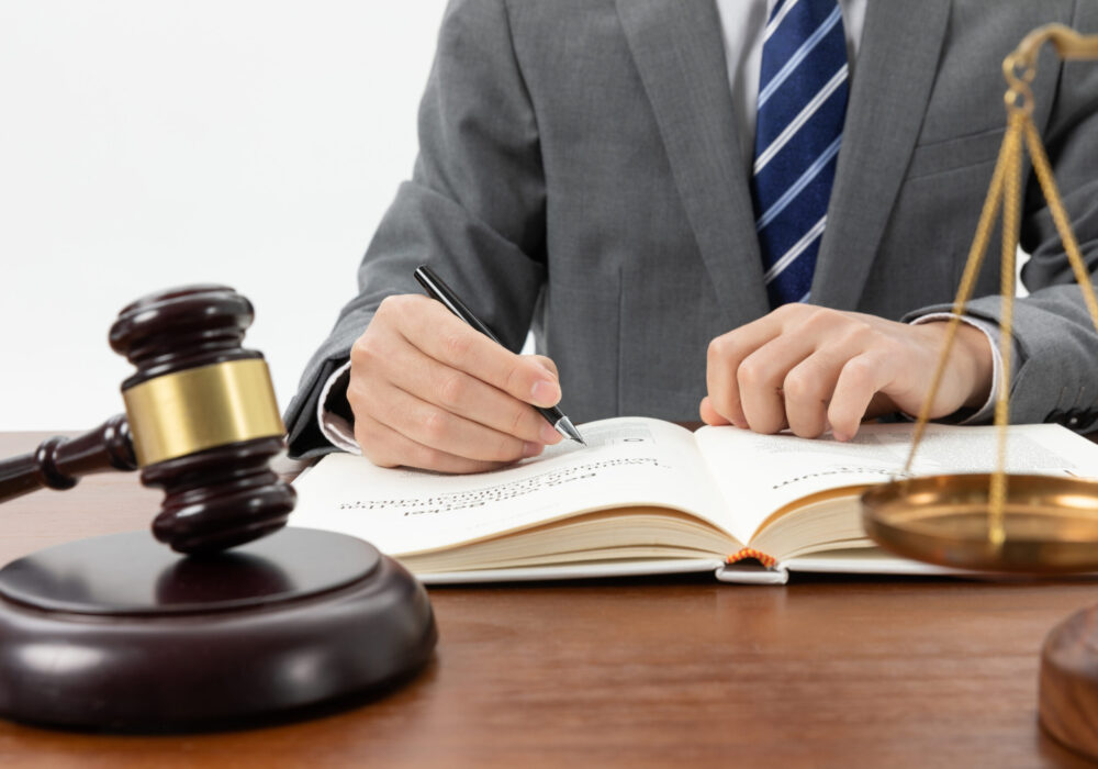 closeup-shot-person-writing-book-with-gavel-table closeup-shot-person-writing-book-with-gavel-table