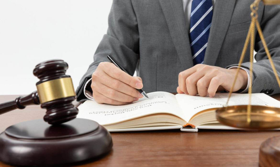 closeup-shot-person-writing-book-with-gavel-table closeup-shot-person-writing-book-with-gavel-table
